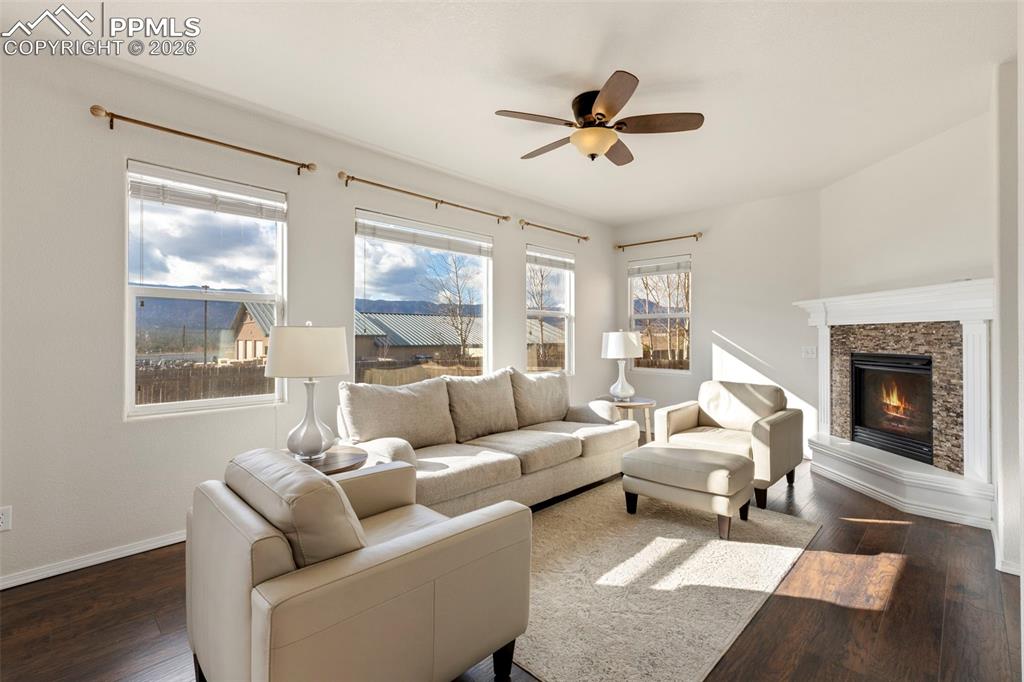 Image 9 of 31: Living room with dark wood-style floors, ceiling fan, and a fireplace