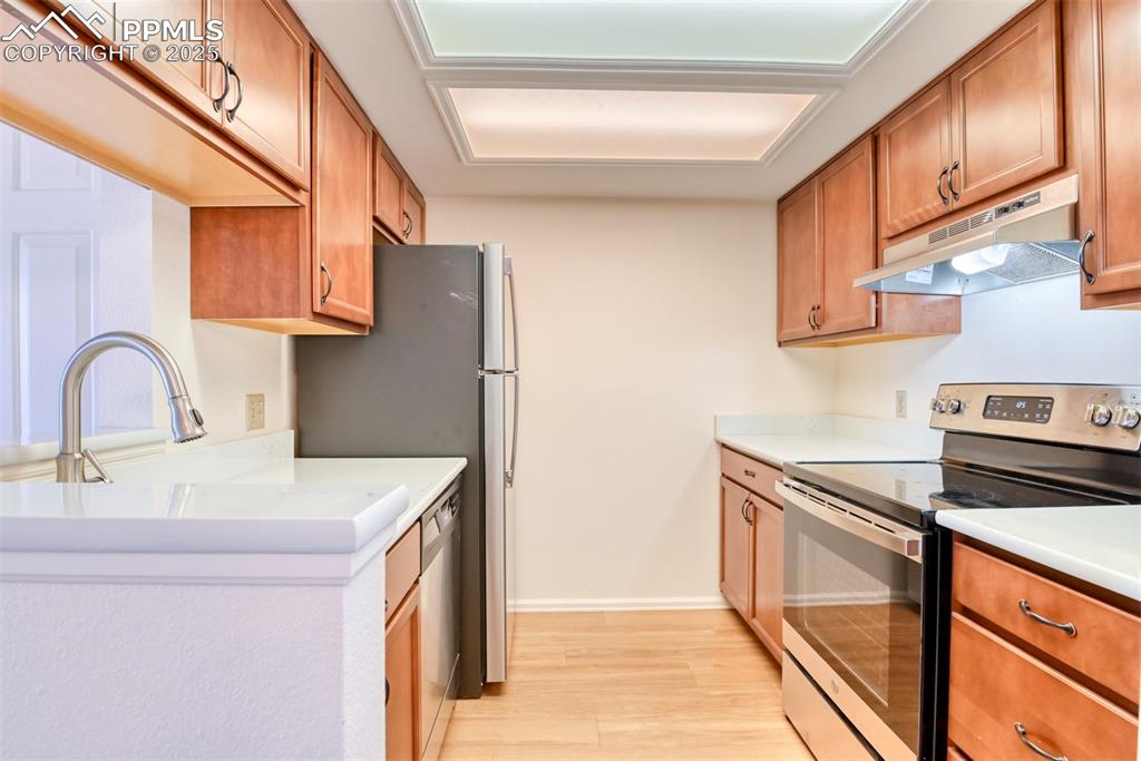 Image 13 of 42: Kitchen featuring stainless steel appliances, under cabinet range hood, lig