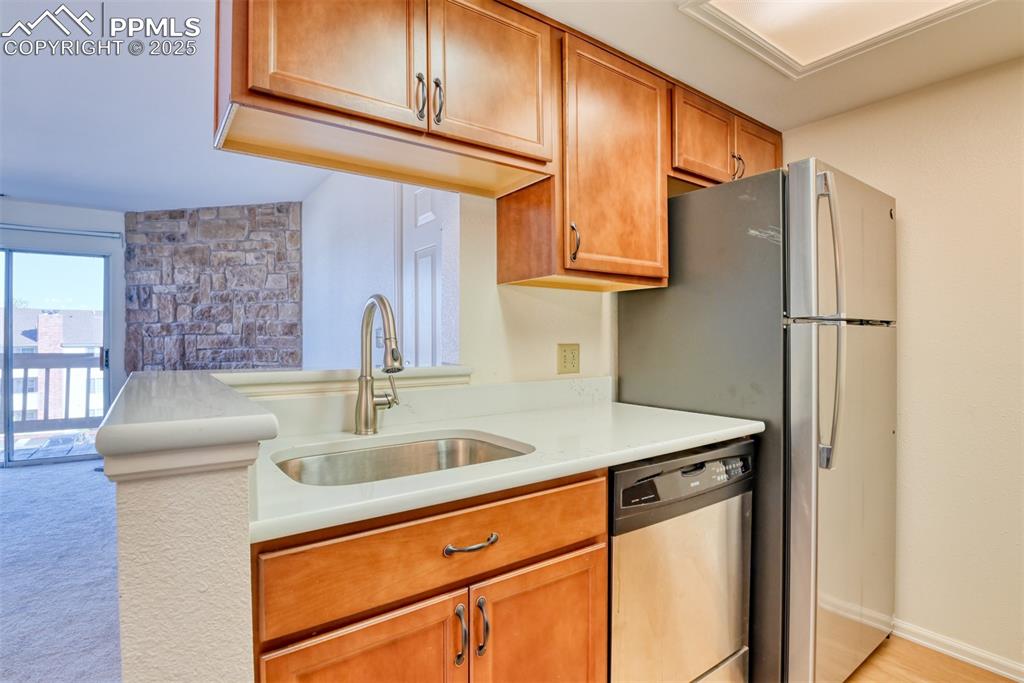 Image 15 of 42: Kitchen featuring appliances with stainless steel finishes, brown cabinetry