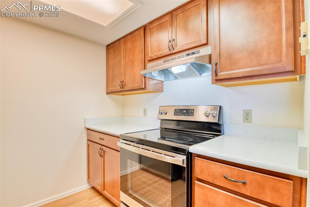 Image 16 of 42: Kitchen featuring stainless steel electric stove, under cabinet range hood,