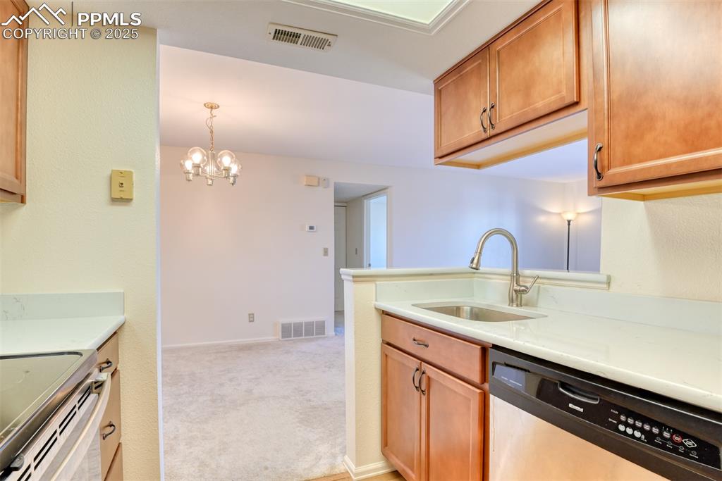 Image 17 of 42: Kitchen featuring dishwasher, a chandelier, hanging light fixtures, white e