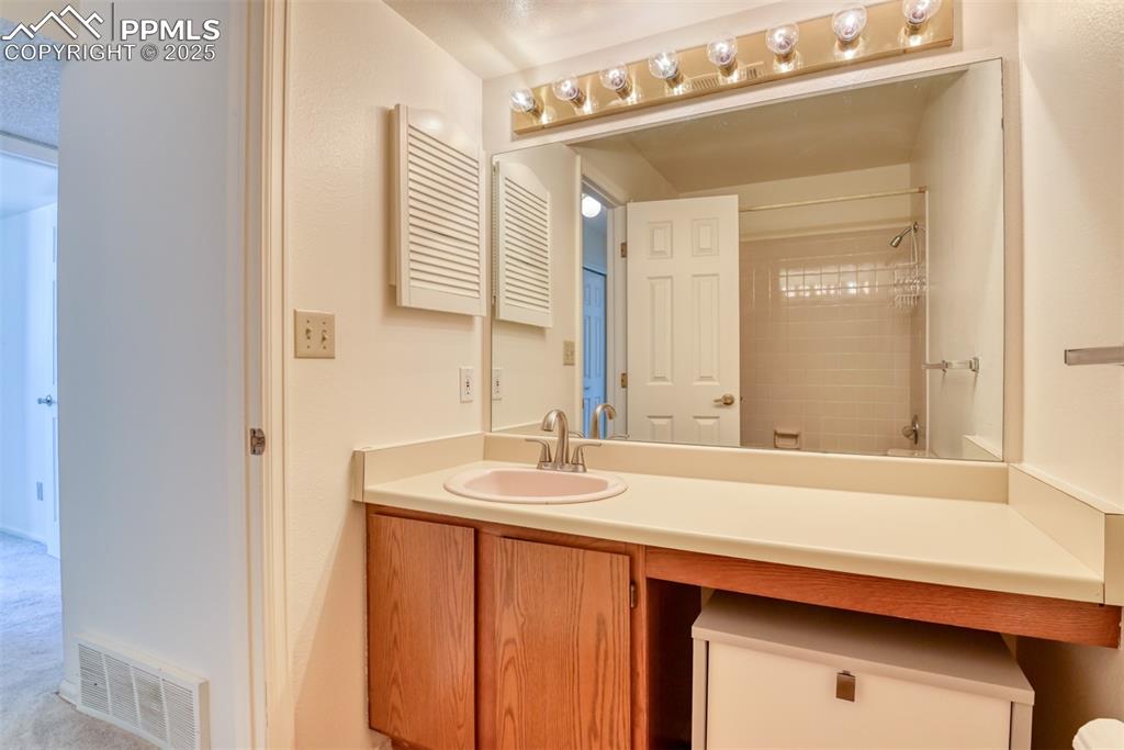 Image 35 of 42: Bathroom with vanity and light colored carpet