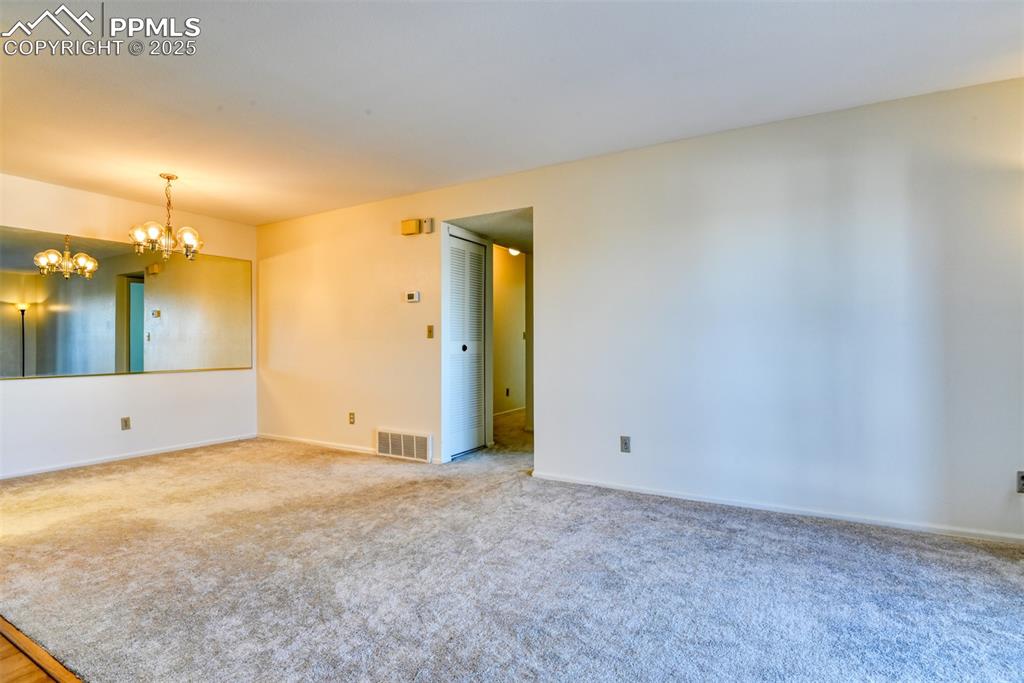 Image 8 of 42: Empty room featuring a chandelier and carpet flooring