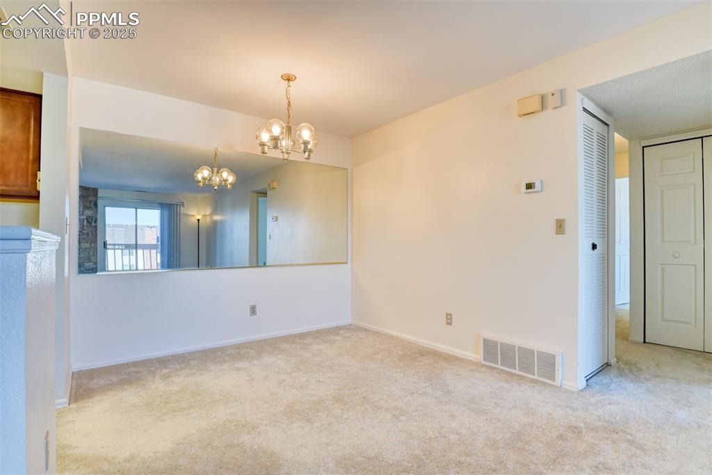Image 9 of 42: Unfurnished room with light colored carpet and a chandelier