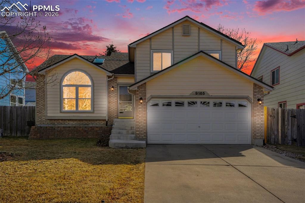Caption: Traditional home with brick siding, concrete driveway, and a garage