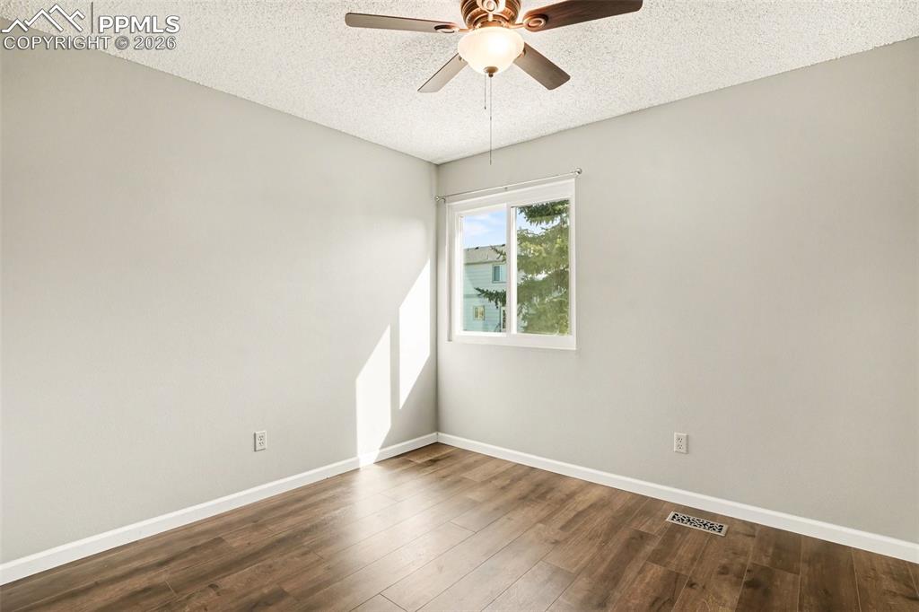 Image 14 of 20: Spare room with dark wood-style floors, a textured ceiling, and ceiling fan