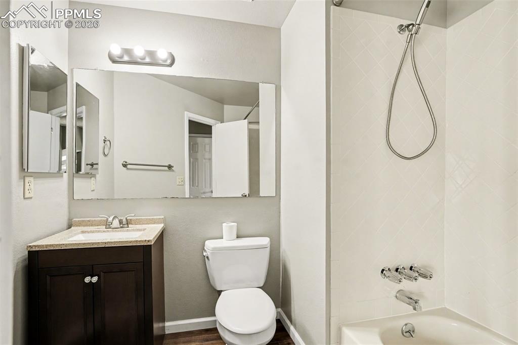 Image 15 of 20: Bathroom with vanity, shower / bathtub combination, and dark wood-type floo