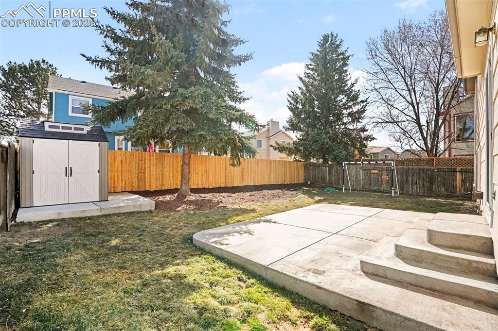 Image 18 of 20: Fenced backyard with a patio and a storage shed