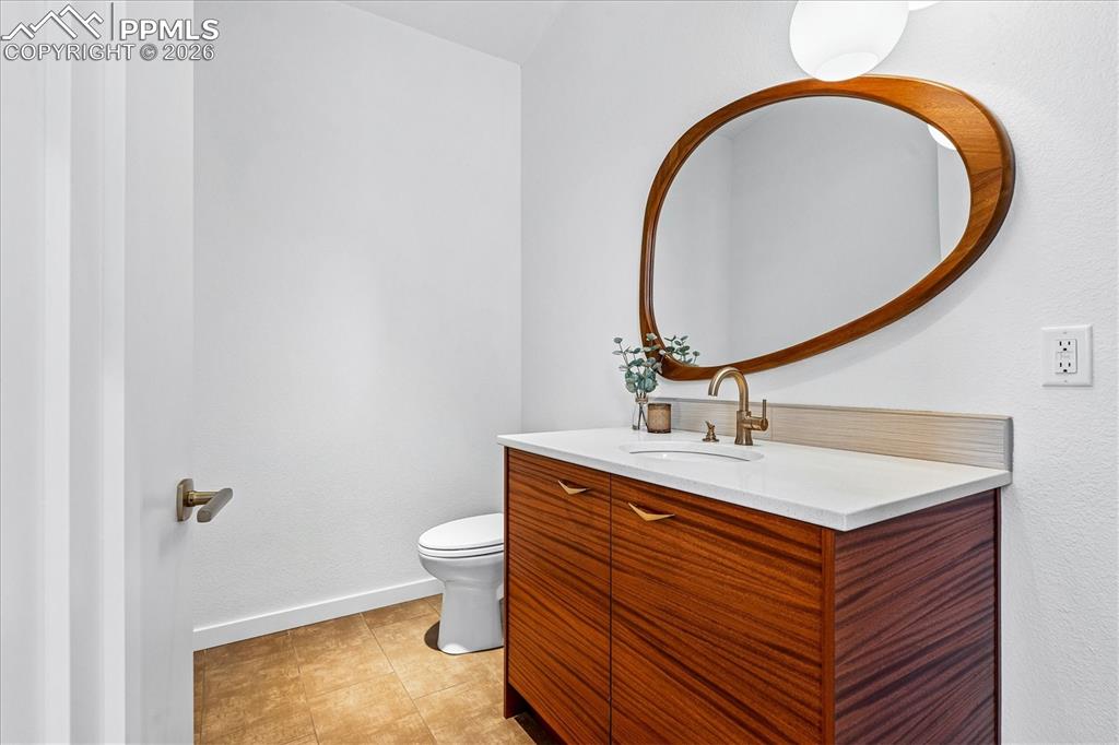 Image 27 of 50: Guest half bath with tile flooring, decorative shelving, chandelier and rec