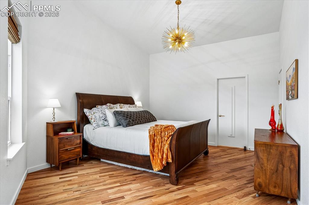 Image 29 of 50: En suite primary bedroom on the main level with solid oak flooring, chandel