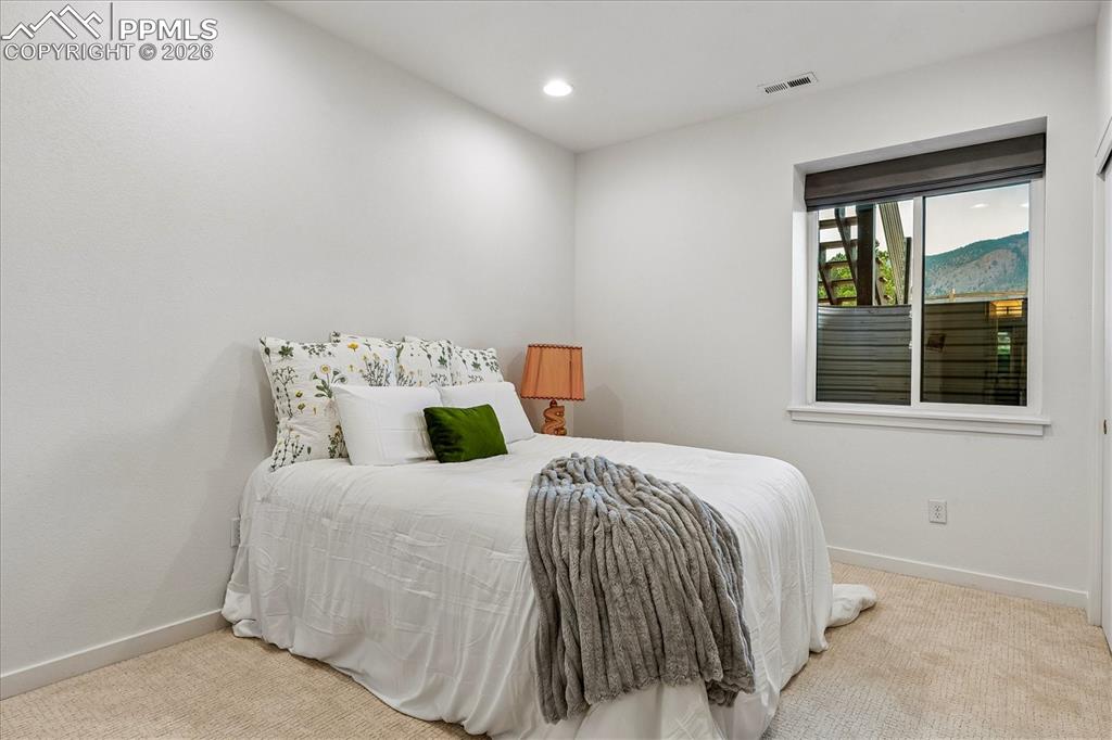 Image 38 of 50: Basement bedroom with new carpet, recessed lighting, and mountain views.