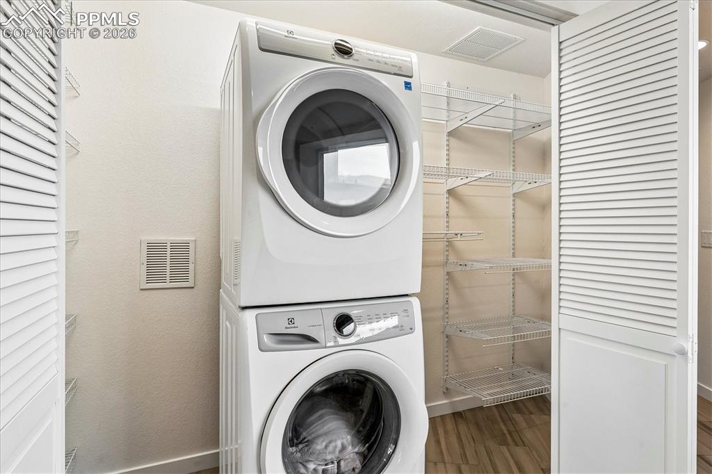 Image 42 of 50: Basement laundry room with heated tile flooring, washer, dryer, storage she