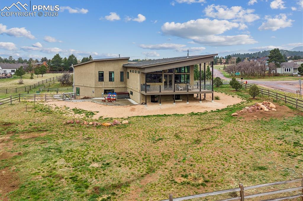 Image 44 of 50: The back side of the home with wrap-around porch on a fenced lot surrounded