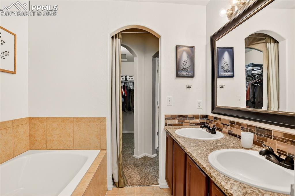 Image 25 of 32: Ensuite Primary Bathroom and Walk-in Closet Beyond