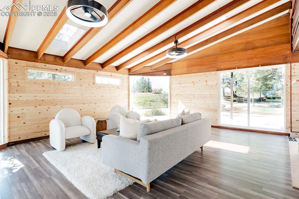 Image 13 of 43: Sun room with wood walls, wood finished floors, plenty of natural light, an