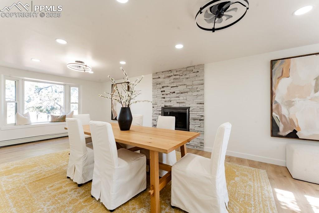 Image 14 of 43: Dining space with light wood finished floors, recessed lighting, a fireplac