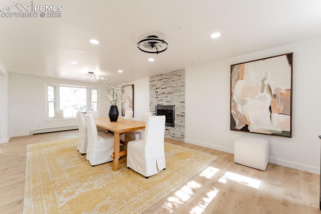 Image 15 of 43: Dining space with light wood-type flooring, a fireplace, recessed lighting,