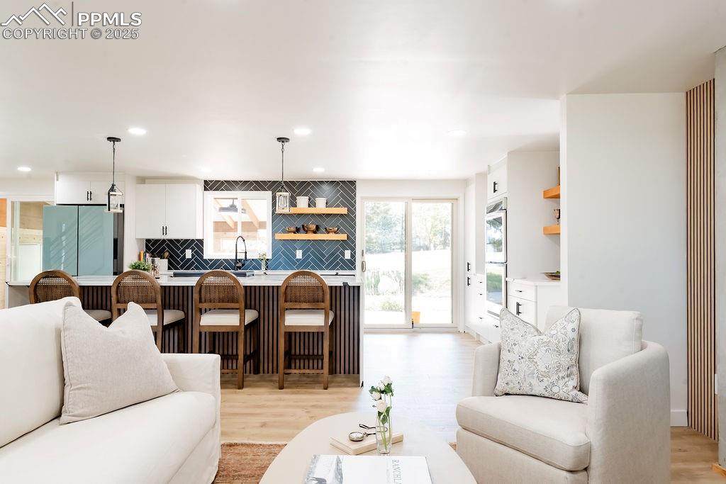 Image 17 of 43: Living room with light wood-style flooring, recessed lighting, and wet bar