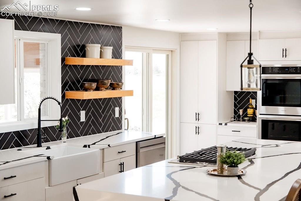 Image 2 of 43: Kitchen featuring backsplash, appliances with stainless steel finishes, whi