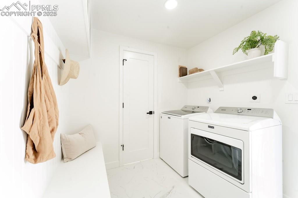 Image 21 of 43: Washroom featuring light marble finish floors, washer and clothes dryer, an