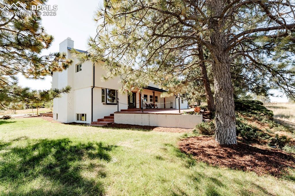 Image 39 of 43: Back of property with stucco siding, a chimney, and a yard