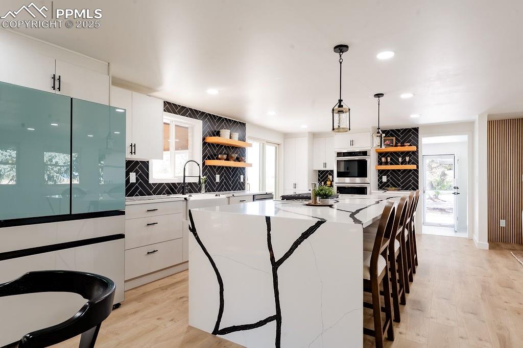 Image 4 of 43: Kitchen featuring white cabinetry, open shelves, tasteful backsplash, frees