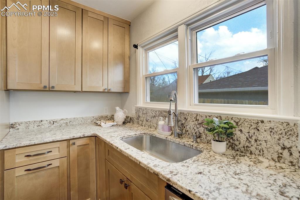 Image 7 of 50: Kitchen featuring light stone countertops, a sink, and light brown cabinetr