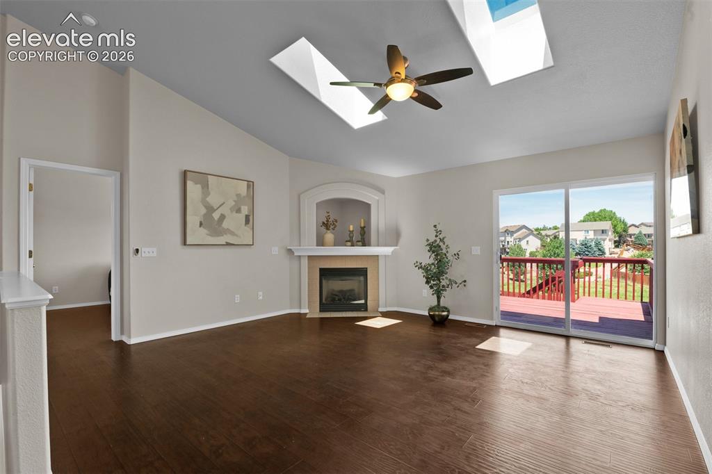 Image 11 of 46: Spacious living area featuring wood-finish flooring, a vaulted ceiling, and