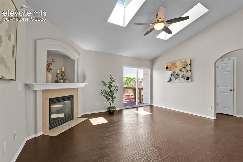 Image 12 of 46: Vaulted ceiling living space featuring skylights, a ceiling fan, and rich w