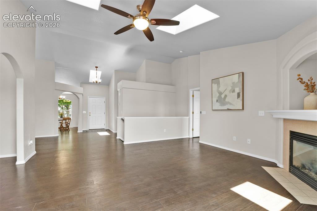 Image 13 of 46: Spacious living area featuring wood-finish flooring, vaulted ceilings with