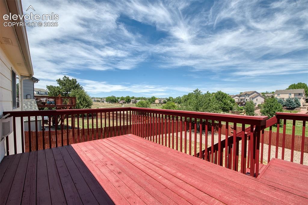 Image 14 of 46: Expansive outdoor deck featuring a red-stained wood surface, full perimeter