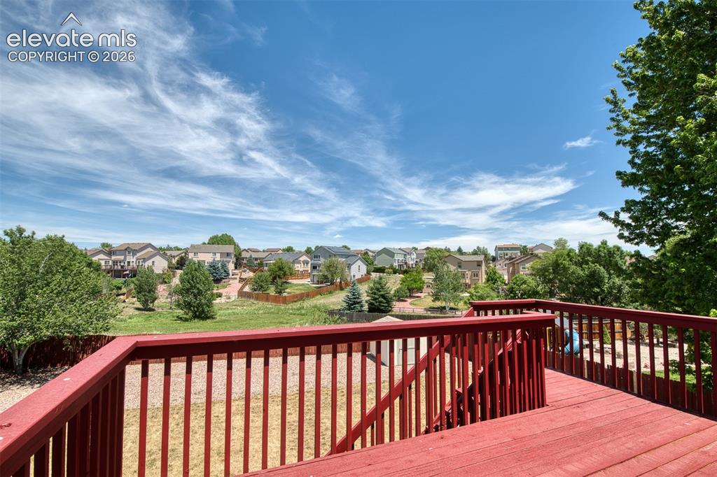 Image 15 of 46: Red-stained wood deck with slatted railings overlooking a landscaped backya