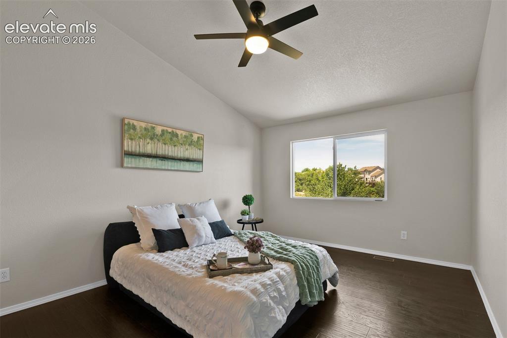 Image 18 of 46: Vaulted ceiling with a ceiling fan, wood-finish flooring, and a large windo