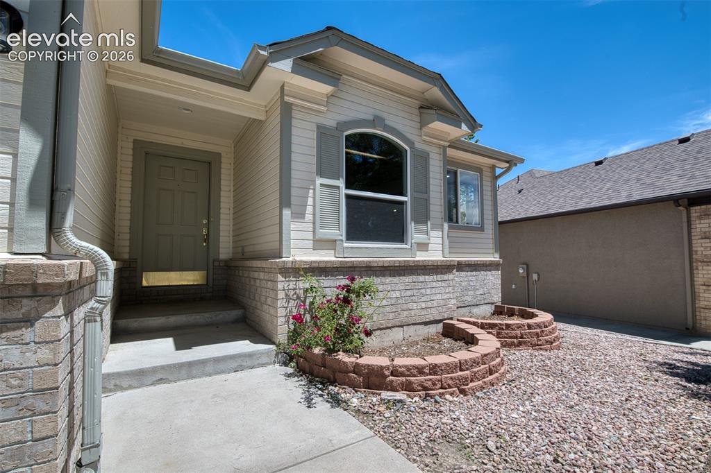 Image 2 of 46: Front exterior featuring panel siding, a covered entry, and a stone facade