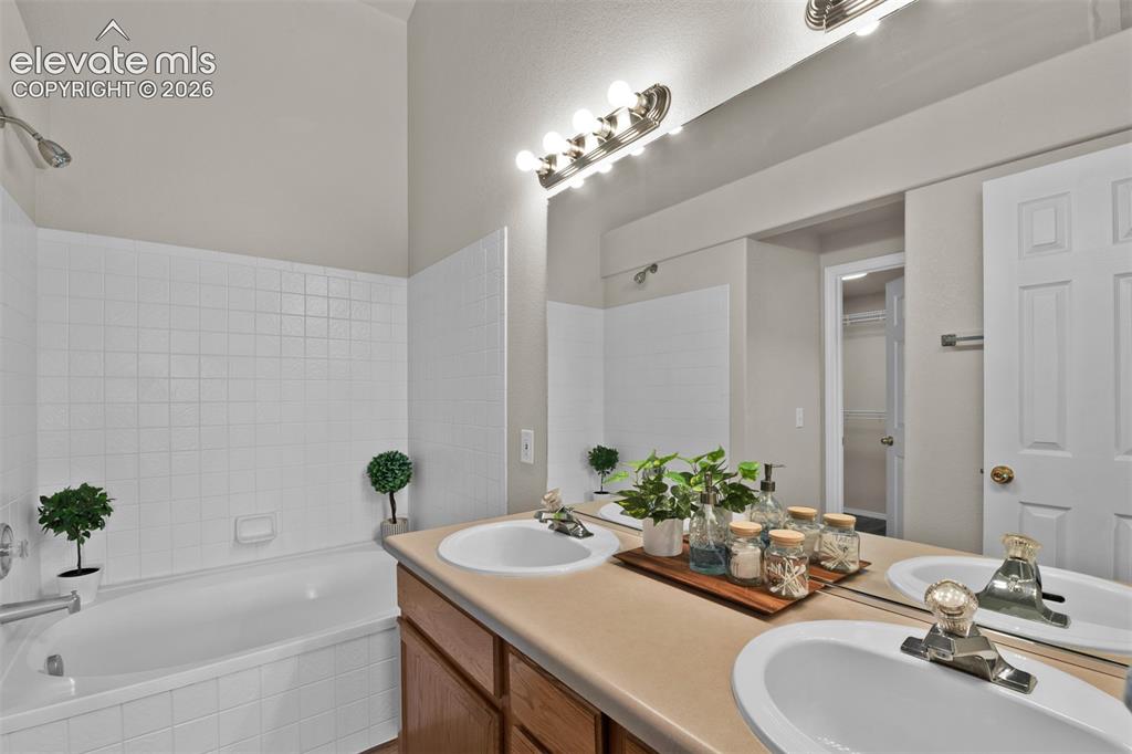 Image 20 of 46: Bathroom featuring a double vanity with integrated sinks, a wide mirror, an