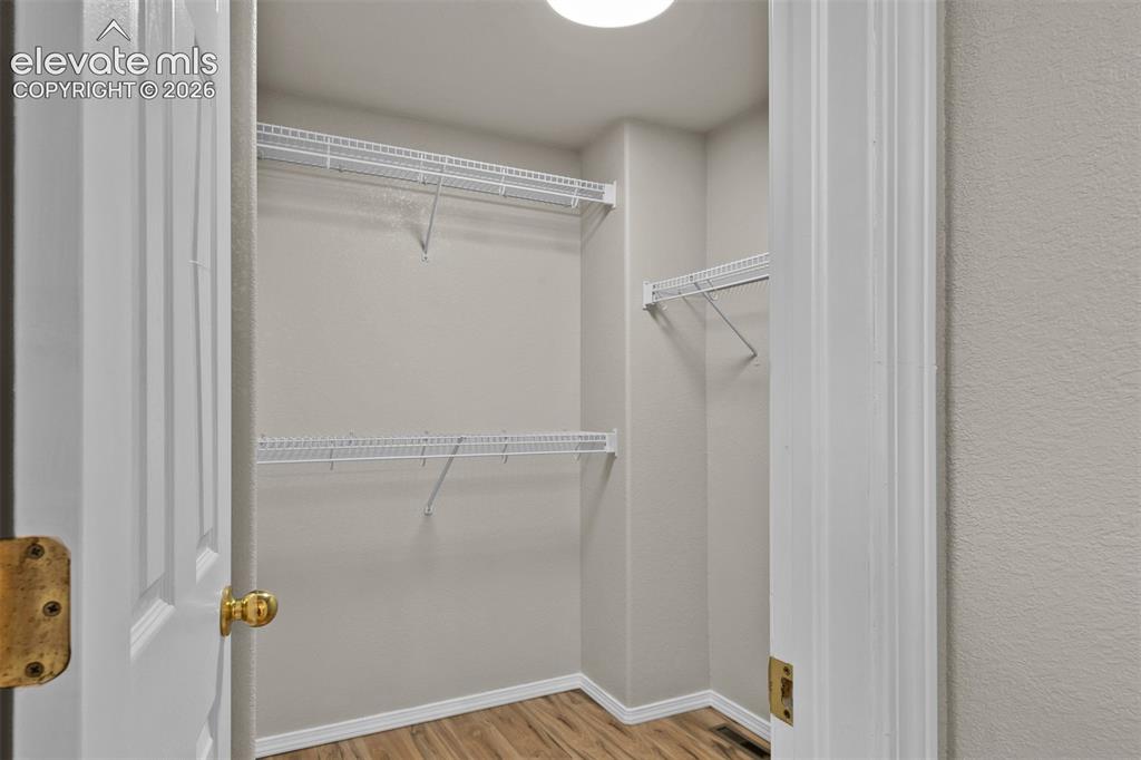 Image 21 of 46: Closet featuring wood-finish flooring, light neutral-toned walls, white wir