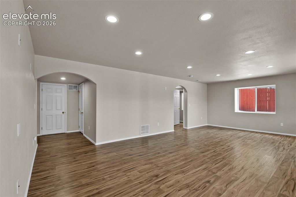 Image 28 of 46: Spacious open-concept room featuring wood-finish flooring, recessed lightin