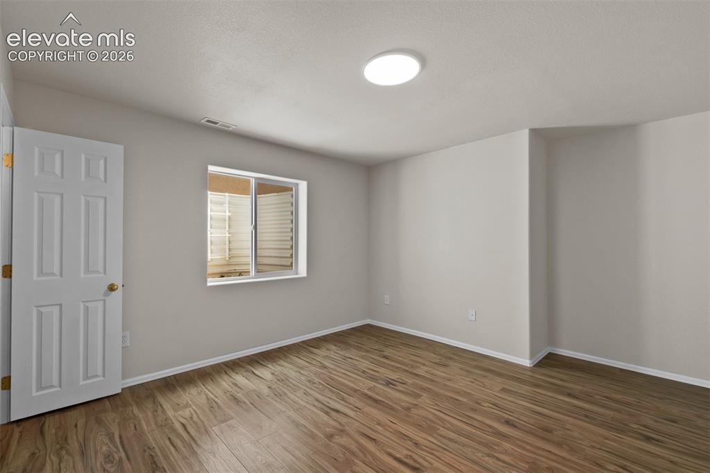 Image 31 of 46: Room featuring wood-finish flooring, a white trim baseboard, and light-tone