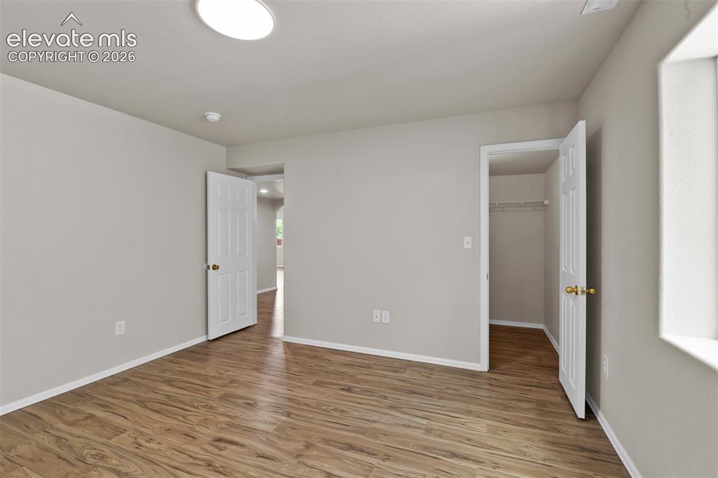 Image 33 of 46: Spacious room featuring wood-finish flooring, light gray walls, a ceiling-m