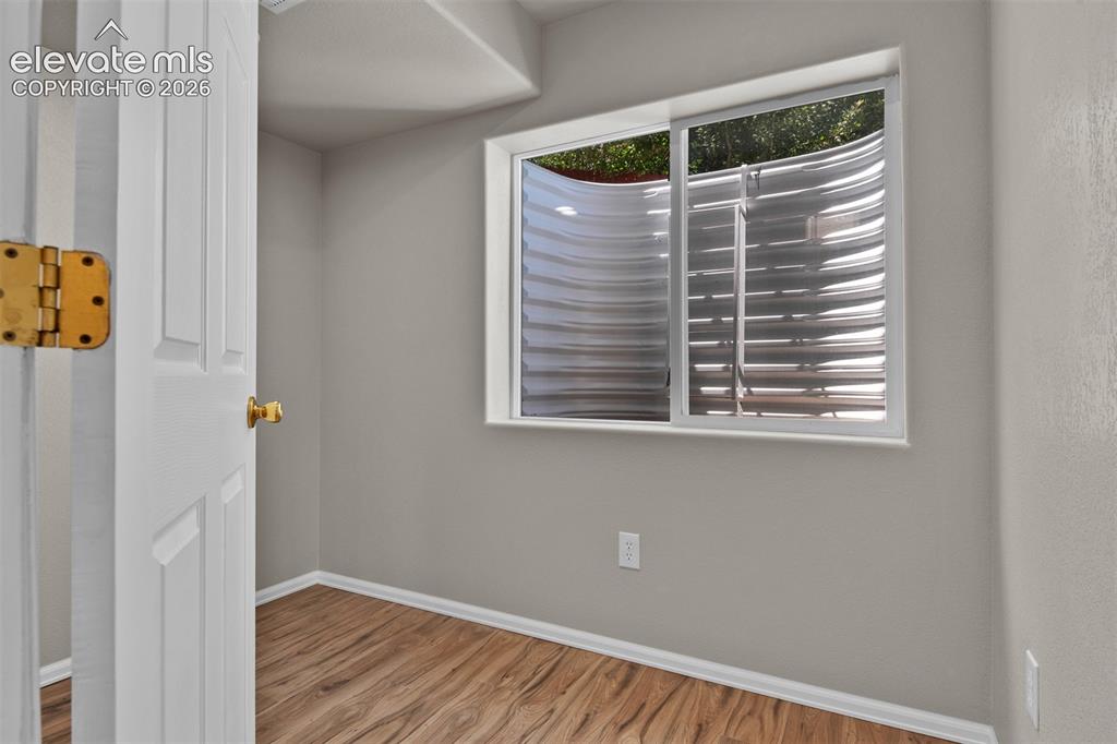 Image 36 of 46: Room with a large egress window and wood-finish flooring