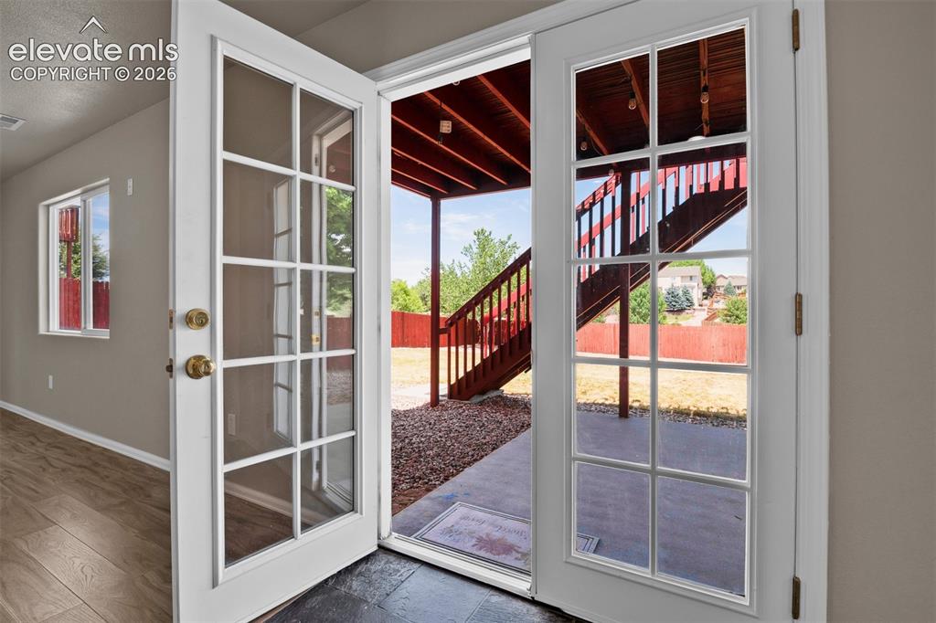 Image 37 of 46: French doors with grid panel glass open to an exterior concrete patio and w