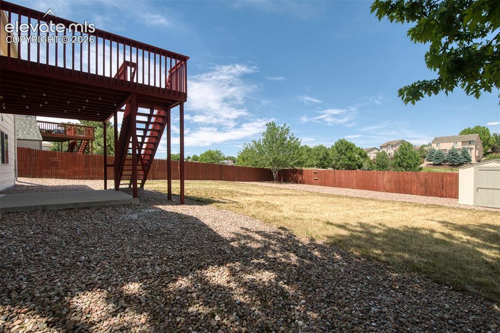 Image 38 of 46: Spacious backyard featuring a multi-level deck with stairs, a ground-level