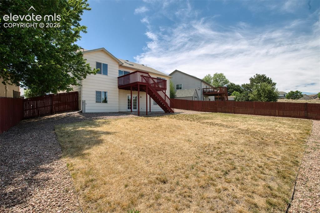 Image 39 of 46: Expansive backyard featuring a partial privacy fence, gravel perimeter, and