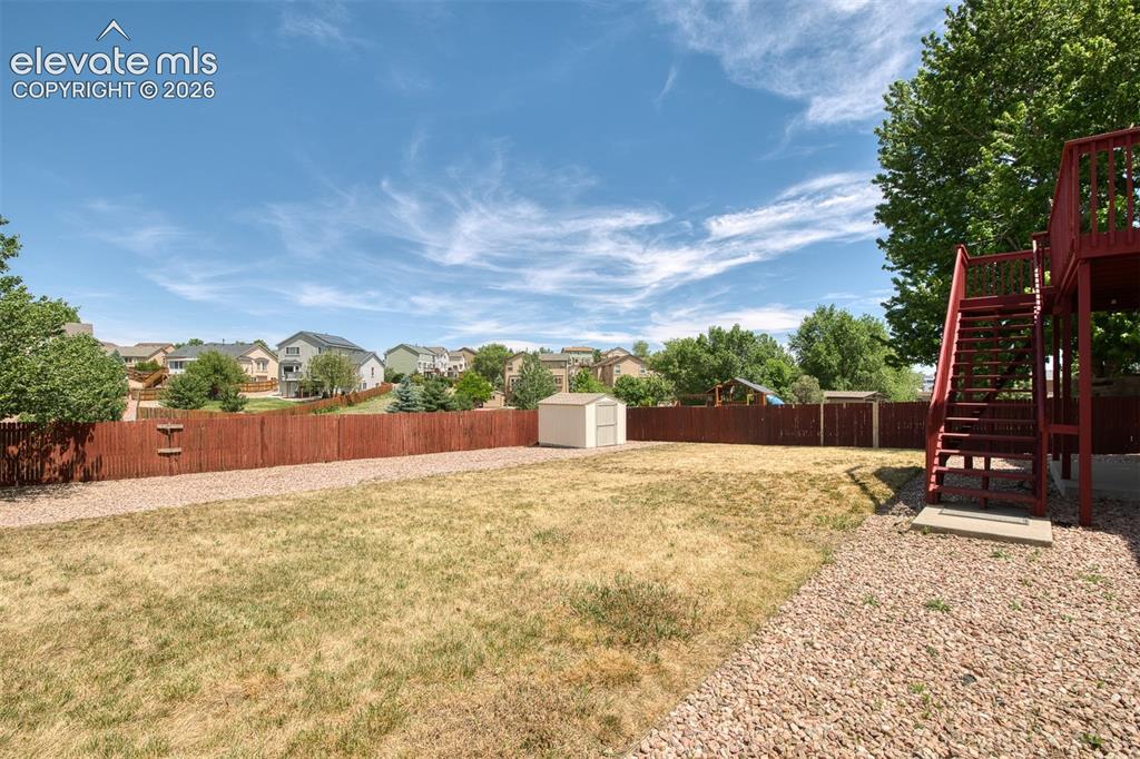 Image 41 of 46: Expansive backyard featuring a red wood privacy fence, gravel perimeter, ma