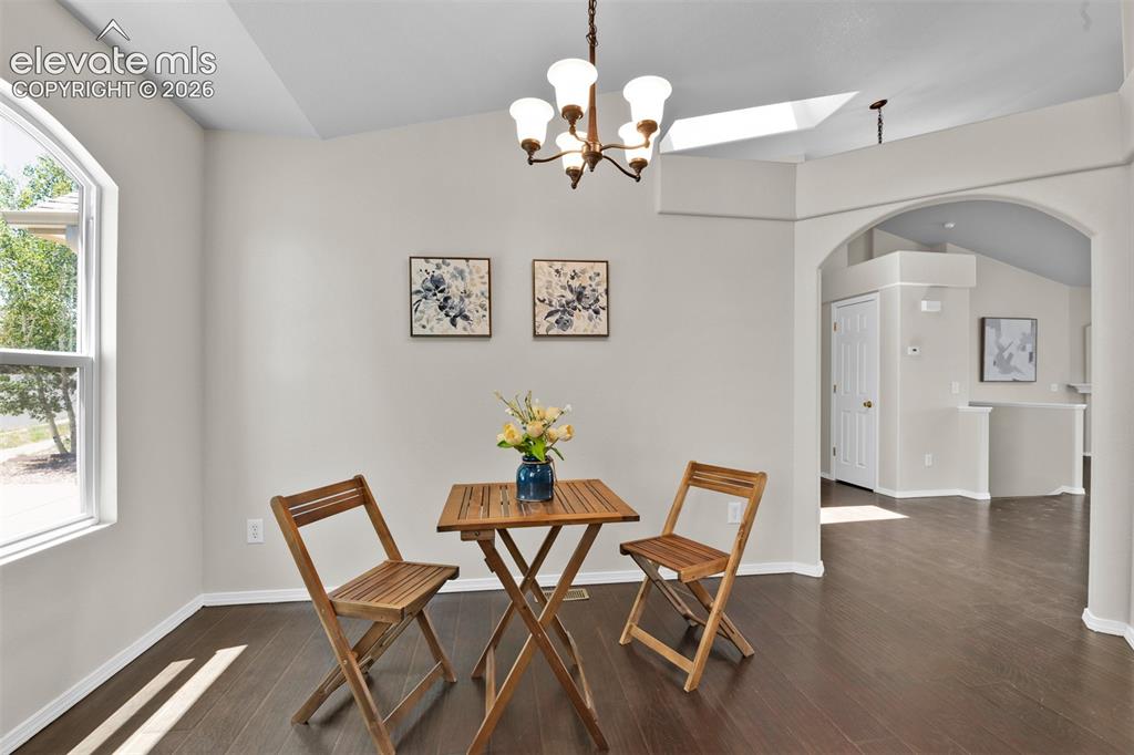 Image 7 of 46: Expansive interior space featuring wood-finish flooring, vaulted ceilings,