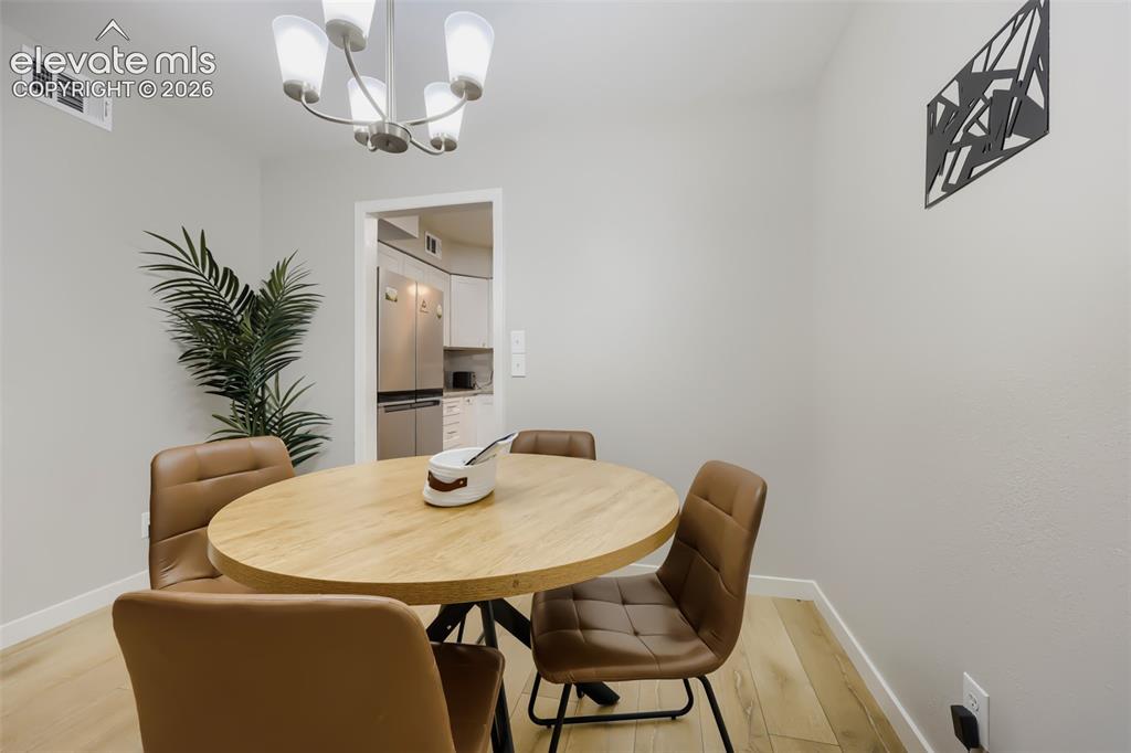 Image 15 of 28: Dining area featuring wood-finish flooring and a contemporary chandelier