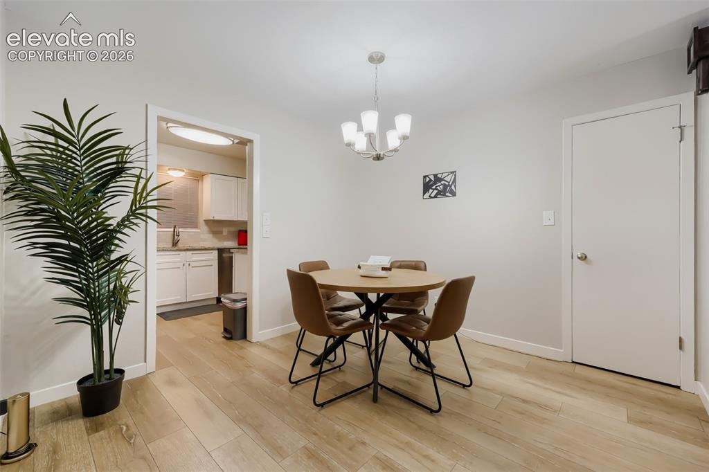 Image 16 of 28: Dining area featuring wood-finish flooring, a contemporary chandelier, and