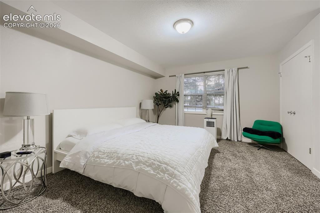 Image 17 of 28: Spacious room featuring neutral painted walls, a window with white curtains