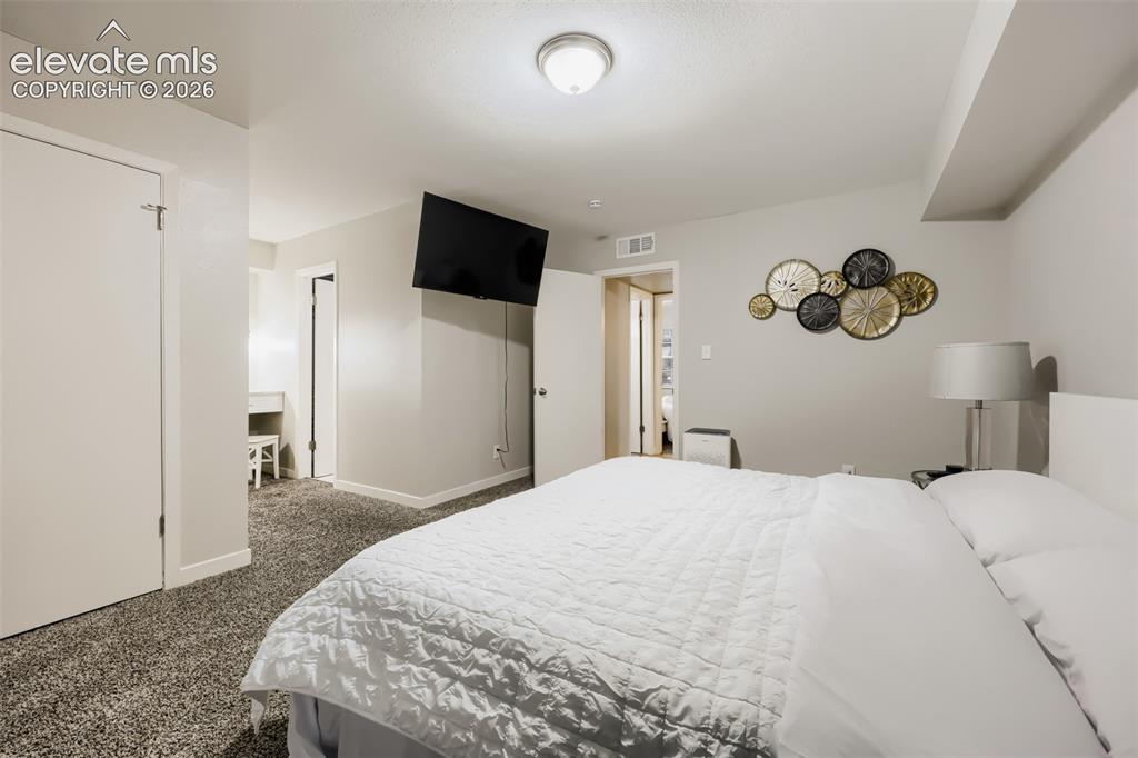 Image 18 of 28: Plush carpet flooring complements a wall-mounted television and a flush-mou