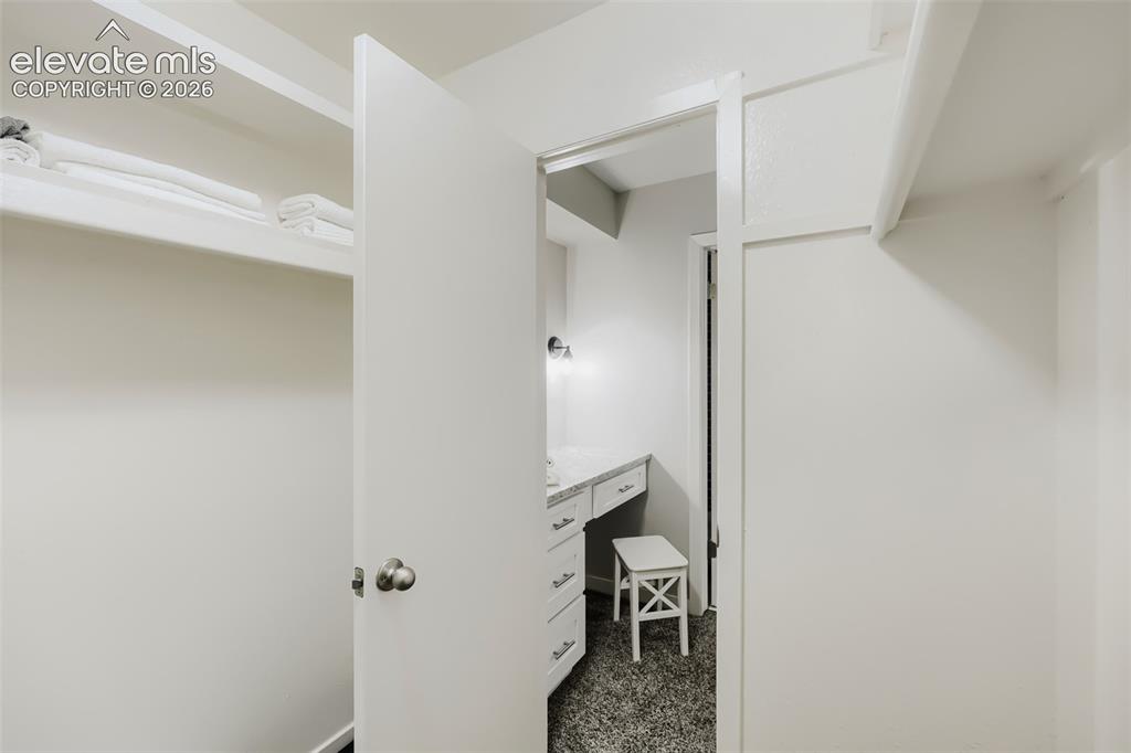 Image 19 of 28: Walk-in closet featuring built-in shelving, white walls, and a white interi